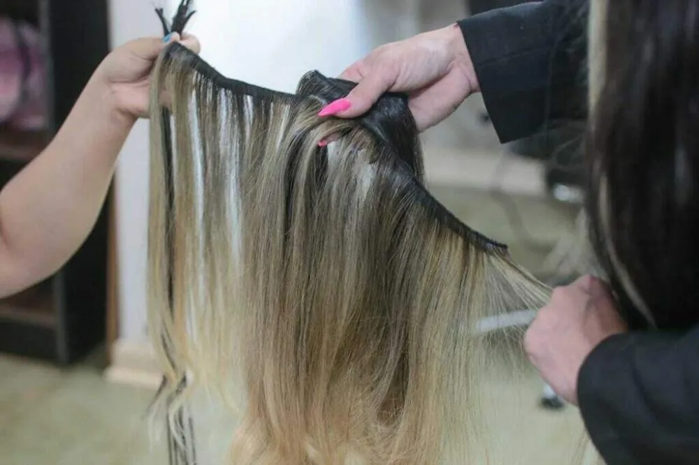 Mechas de cabelo humano sendo manipulados por cabeleireira. (Foto: Arquivo/Campo Grande News)